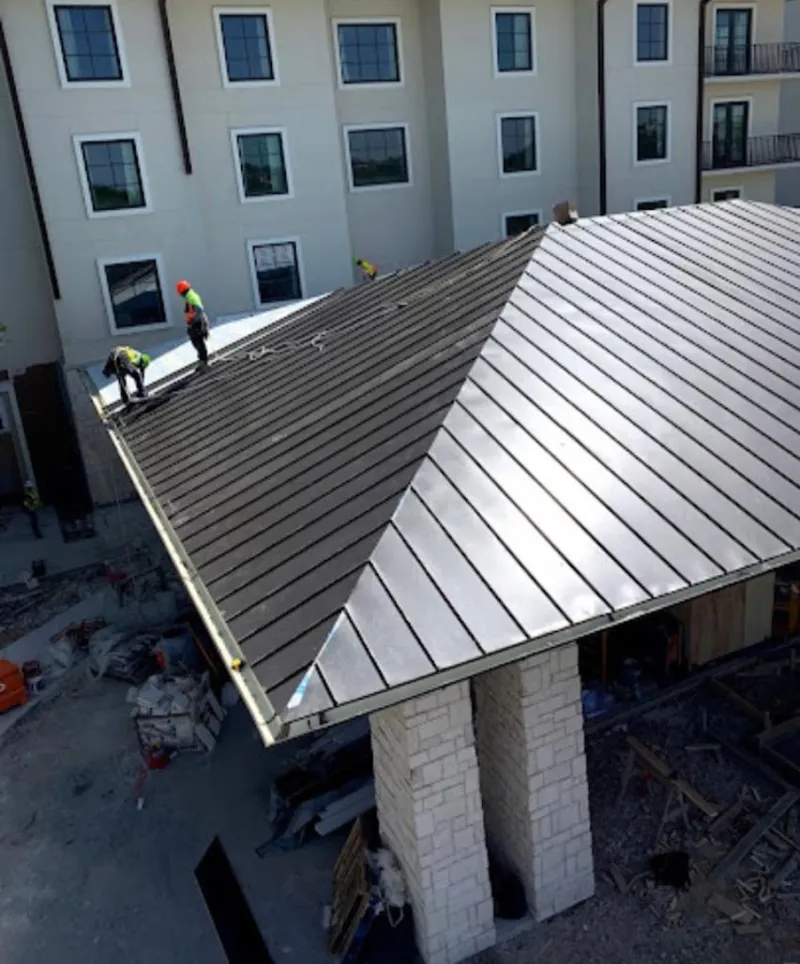 Crew installing standing seam metal roof panels on a commercial project in Palm Tree